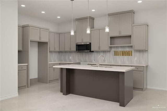 9206 N 25th St, Mcallen, TX 78504 - kitchen with gray cabinets, a kitchen island with sink, stainless steel microwave, tasteful backsplash, and recessed lighting