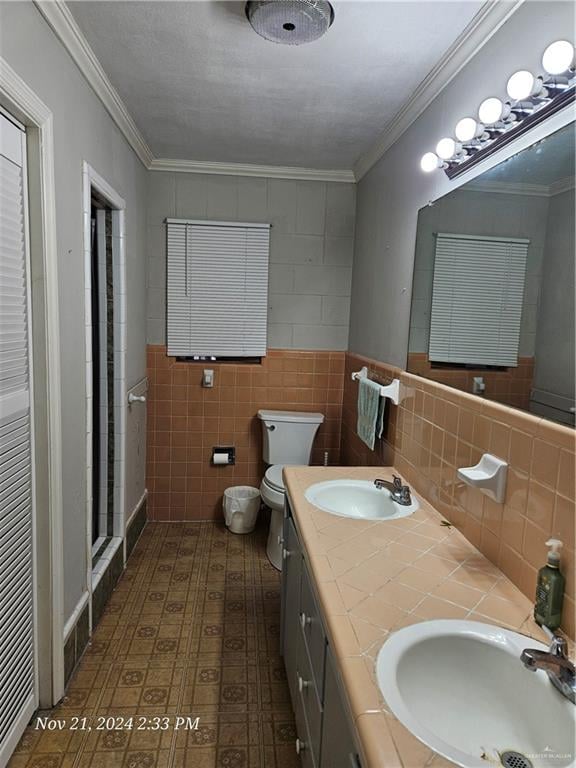 bathroom featuring vanity, crown molding, toilet, tile walls, and an enclosed shower