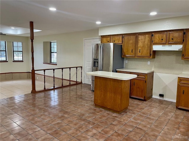 5307 Fm 493rd Rd, Donna, TX 78537 - kitchen featuring under cabinet range hood, brown cabinetry, a center island, tile patterned flooring, and light countertops