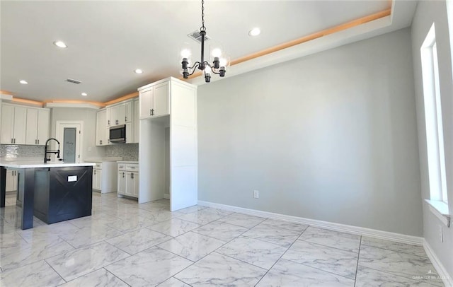 kitchen with recessed lighting, stainless steel microwave, marble finish floor, and a chandelier