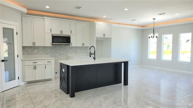 kitchen with hanging light fixtures, a sink, marble finish floor, stainless steel microwave, and visible vents