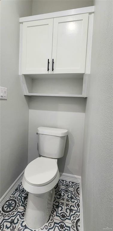 bathroom featuring baseboards, tile patterned floors, and toilet