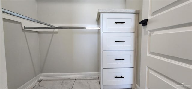 walk in closet with marble finish floor