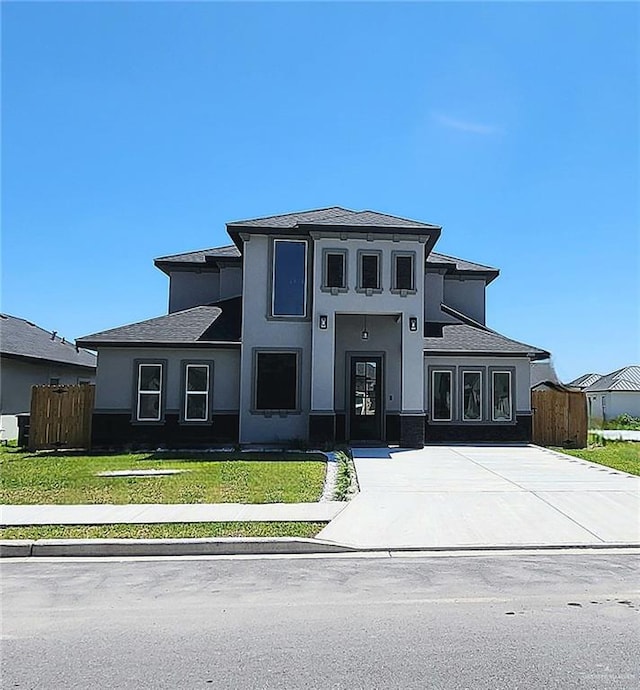 view of front of house with fence, a front lawn, and stucco siding