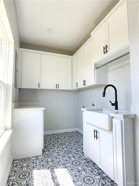 laundry room with cabinet space, a sink, baseboards, hookup for a washing machine, and light tile patterned flooring