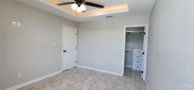 unfurnished bedroom with visible vents, a closet, marble finish floor, a spacious closet, and a tray ceiling