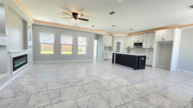 kitchen with open floor plan, a sink, stainless steel microwave, and light countertops