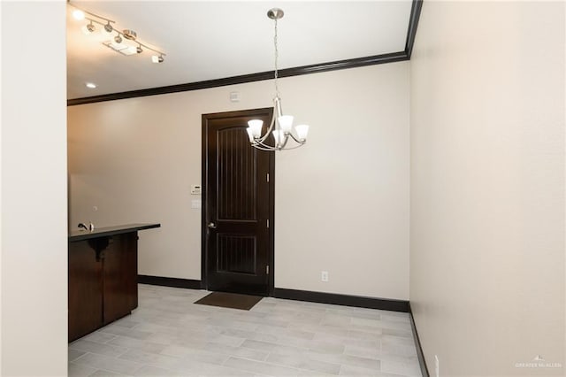 unfurnished dining area featuring ornamental molding, baseboards, and an inviting chandelier