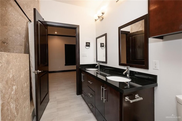 bathroom with double vanity, a shower with curtain, toilet, and a sink