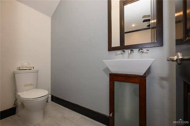 half bath featuring a sink, toilet, and baseboards