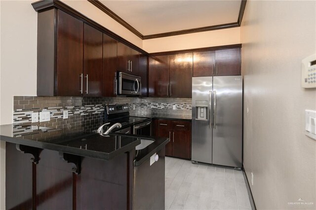 kitchen featuring appliances with stainless steel finishes, dark countertops, crown molding, and dark brown cabinetry