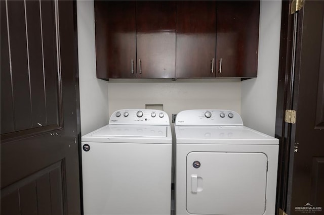 clothes washing area with washer and dryer and cabinet space