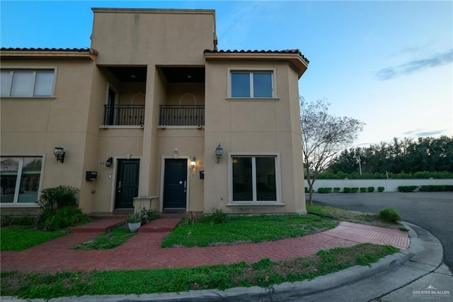 view of front facade with a balcony and stucco siding