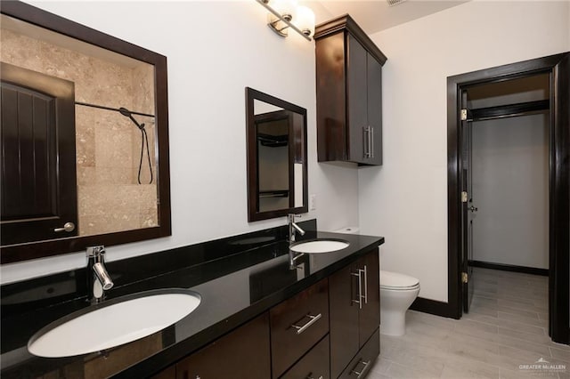 full bathroom featuring double vanity, a sink, toilet, and baseboards