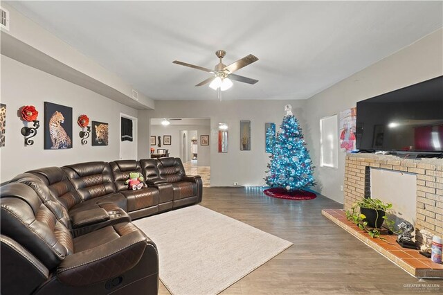 living room featuring ceiling fan, wood-type flooring, and a fireplace