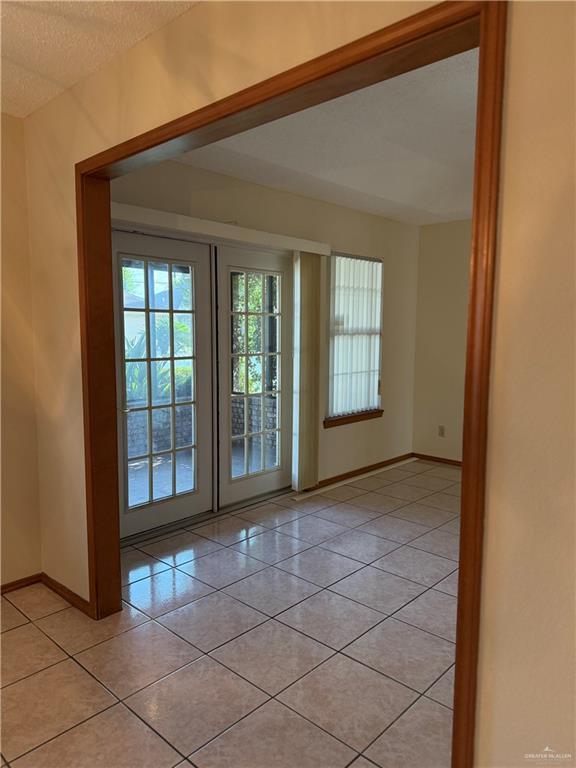 2303 Viola St, Mission, TX 78574 - doorway to outside featuring a textured ceiling, baseboards, a healthy amount of sunlight, and light tile patterned floors