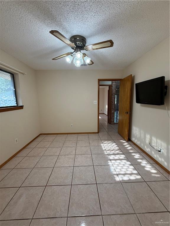 2303 Viola St, Mission, TX 78574 - empty room featuring baseboards, ceiling fan, light tile patterned flooring, and a textured ceiling