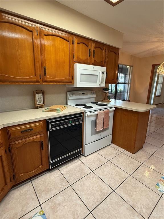 2303 Viola St, Mission, TX 78574 - kitchen featuring brown cabinetry, a peninsula, white appliances, light countertops, and light tile patterned floors