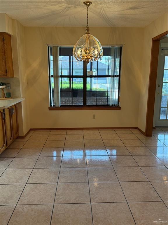 2303 Viola St, Mission, TX 78574 - unfurnished dining area with light tile patterned flooring, an inviting chandelier, and a wealth of natural light