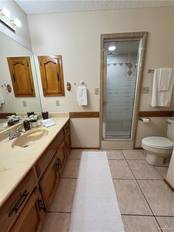 2303 Viola St, Mission, TX 78574 - bathroom with toilet, a textured ceiling, tile patterned flooring, and a stall shower