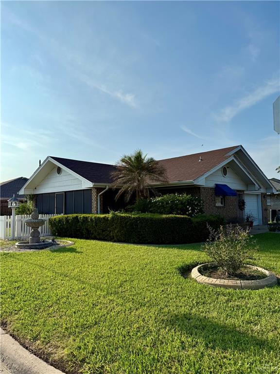 2303 Viola St, Mission, TX 78574 - view of side of home featuring a lawn, fence, and brick siding