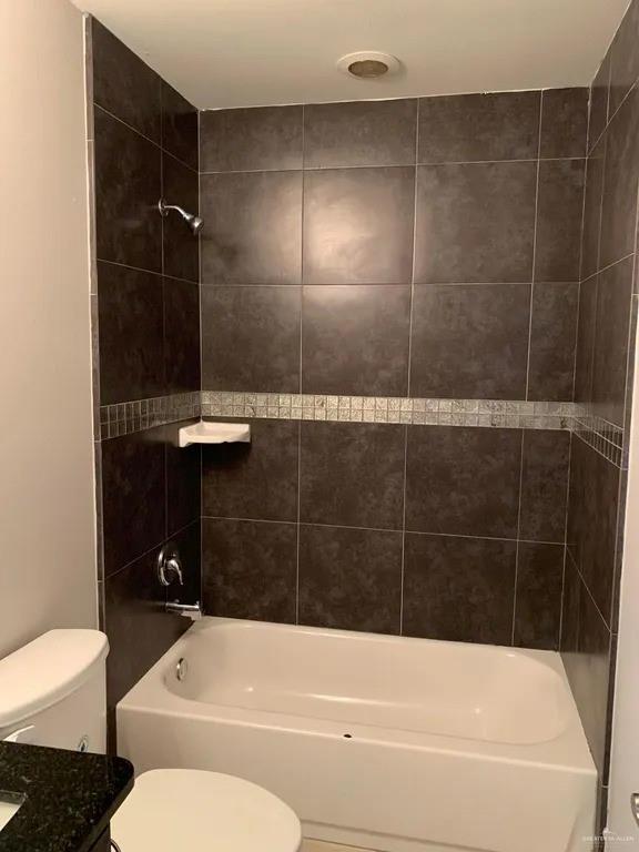 full bathroom with tiled shower / bath combo, vanity, and toilet