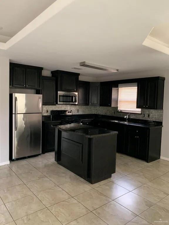 kitchen with backsplash, light tile patterned floors, stainless steel appliances, and a kitchen island