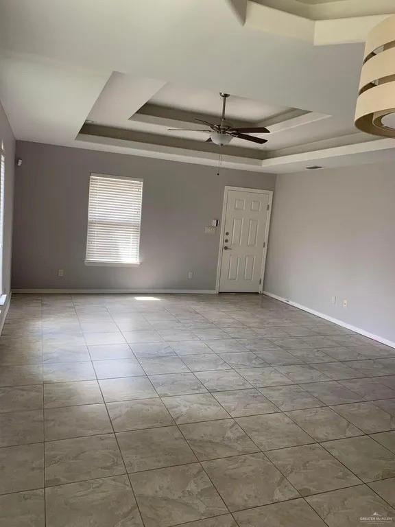 spare room with ceiling fan and a raised ceiling