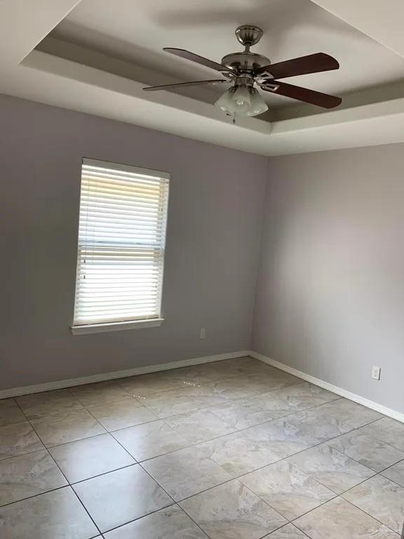 spare room with ceiling fan and a tray ceiling