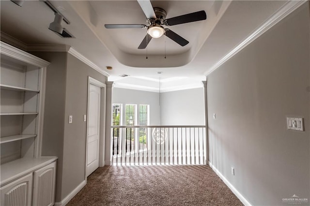 corridor featuring carpet flooring, baseboards, crown molding, and a raised ceiling