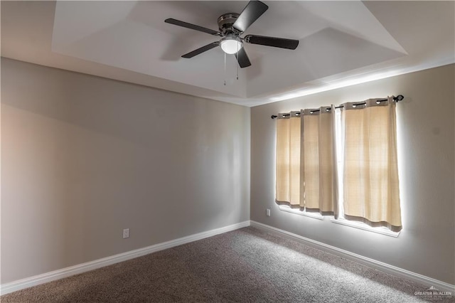 spare room featuring ceiling fan, a raised ceiling, carpet, and baseboards