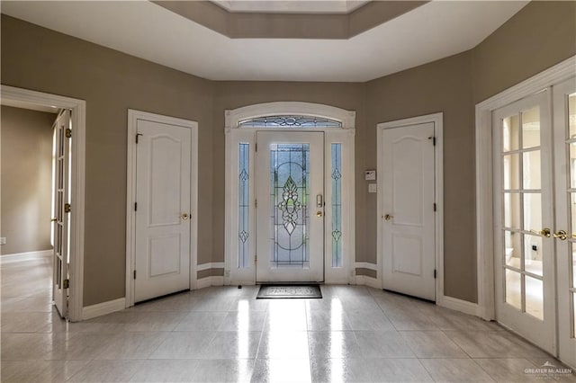 foyer entrance with french doors, light tile patterned floors, and baseboards
