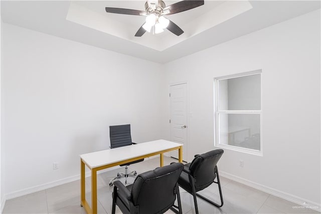 office area with a raised ceiling, ceiling fan, and light tile patterned flooring