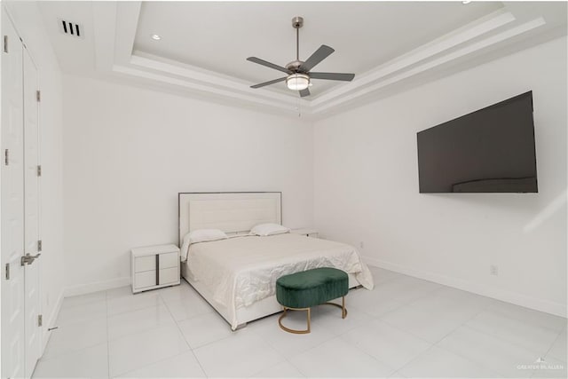 tiled bedroom with ceiling fan and a tray ceiling