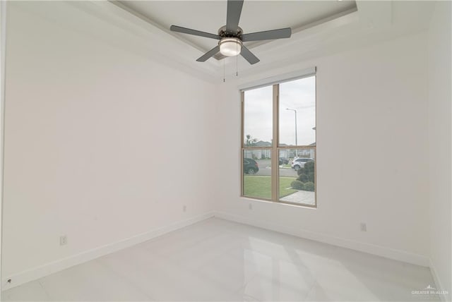 spare room featuring ceiling fan, light tile patterned flooring, and a raised ceiling