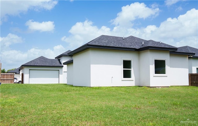 rear view of property with a garage and a yard