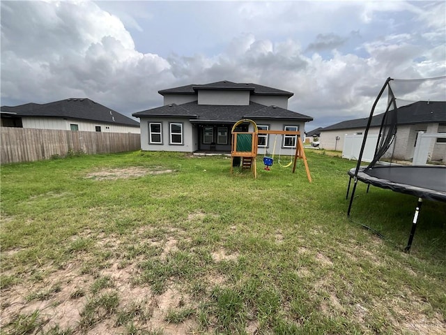 1213 Emma Elizabeth St, Weslaco, TX 78599 - rear view of house featuring a trampoline, a playground, a shingled roof, and stucco siding