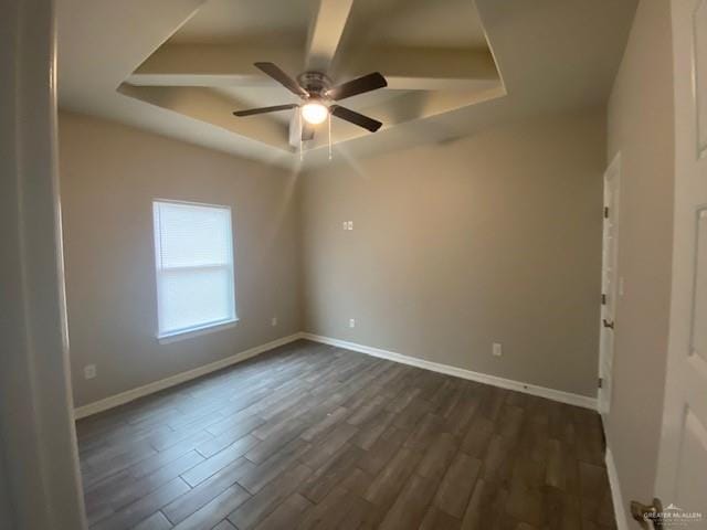 unfurnished room with a raised ceiling, ceiling fan, and dark hardwood / wood-style floors