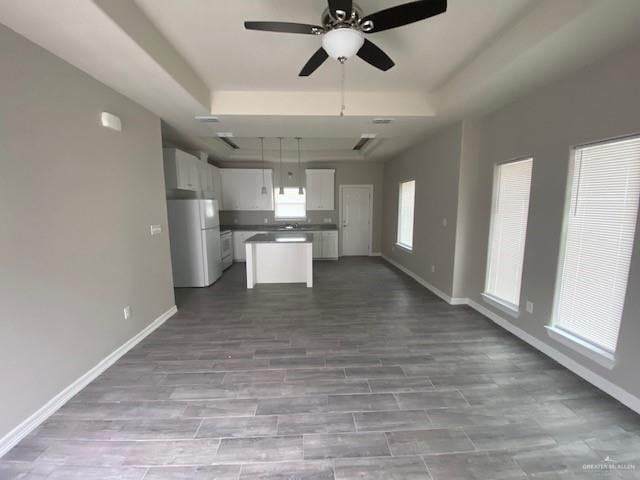 kitchen with a center island, hanging light fixtures, white refrigerator, light hardwood / wood-style floors, and white cabinets