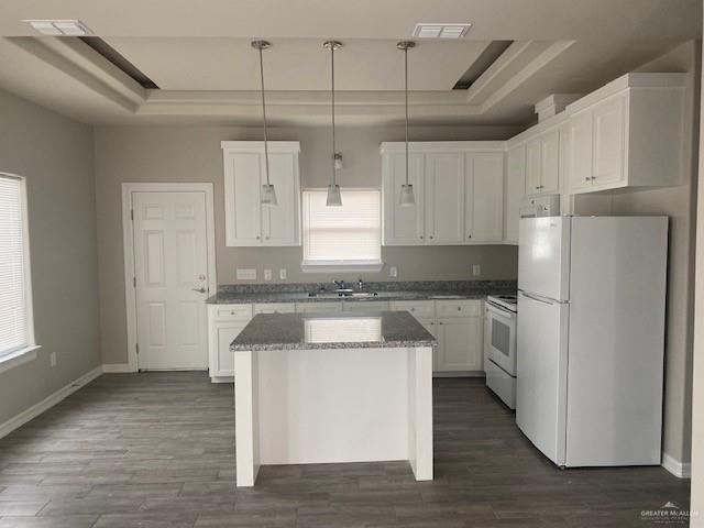 kitchen featuring white cabinetry, a center island, a healthy amount of sunlight, pendant lighting, and white appliances