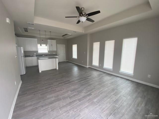 kitchen featuring white fridge, white cabinetry, a tray ceiling, and light hardwood / wood-style flooring