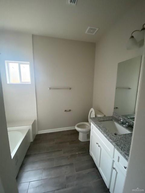 bathroom featuring vanity, hardwood / wood-style flooring, toilet, and a tub