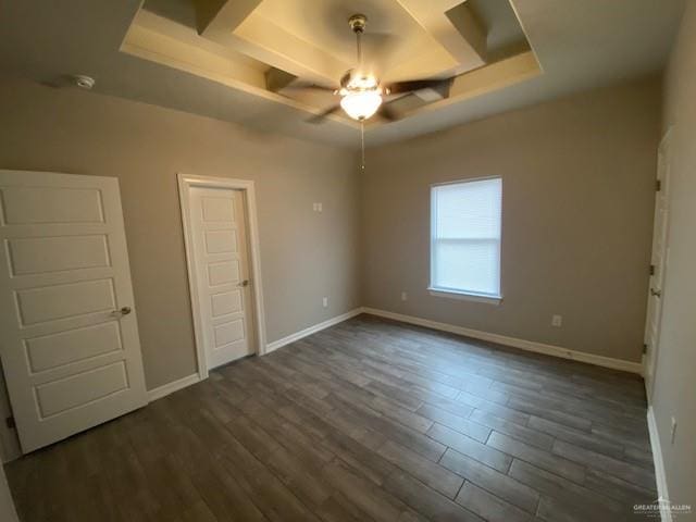 unfurnished bedroom with a raised ceiling, ceiling fan, and dark wood-type flooring