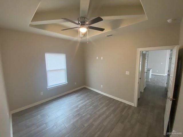 unfurnished room with a raised ceiling, ceiling fan, and dark hardwood / wood-style floors