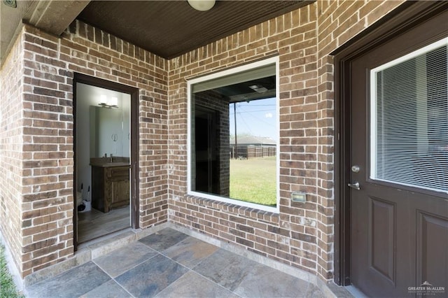 view of exterior entry featuring brick siding