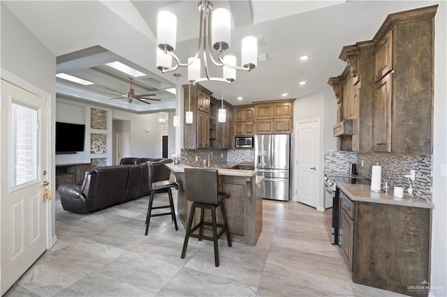 kitchen featuring coffered ceiling, a breakfast bar area, open floor plan, a peninsula, and stainless steel appliances