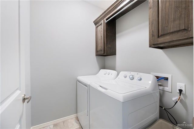 laundry area featuring washing machine and dryer, cabinet space, and baseboards