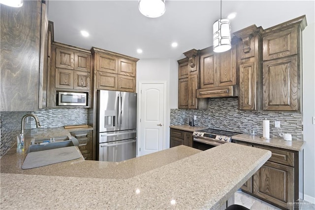 kitchen featuring stainless steel appliances, a peninsula, a sink, backsplash, and pendant lighting