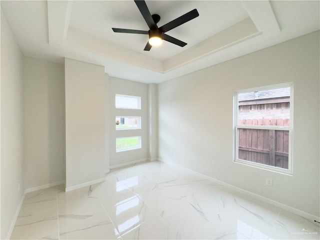 spare room with ceiling fan and a raised ceiling