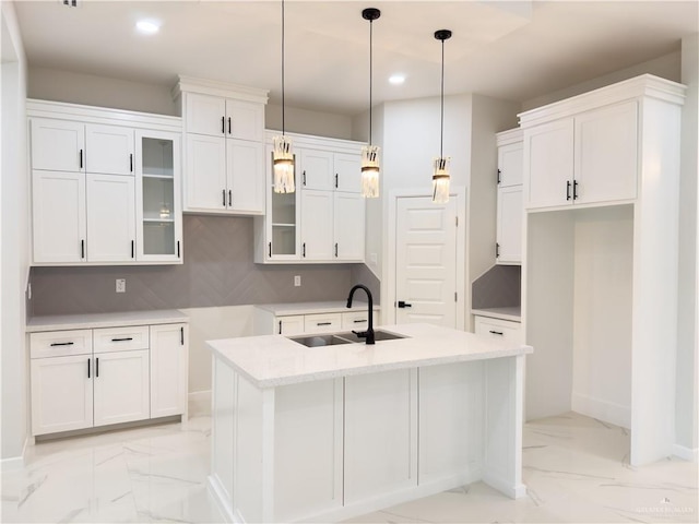 kitchen with sink, white cabinetry, tasteful backsplash, a center island with sink, and decorative light fixtures